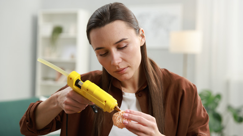 Woman using hot glue gun to make craft