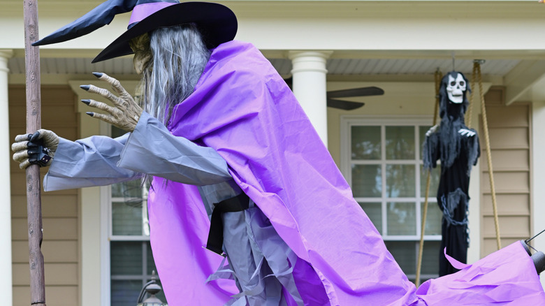 A front yard with a Halloween witch animatronic.