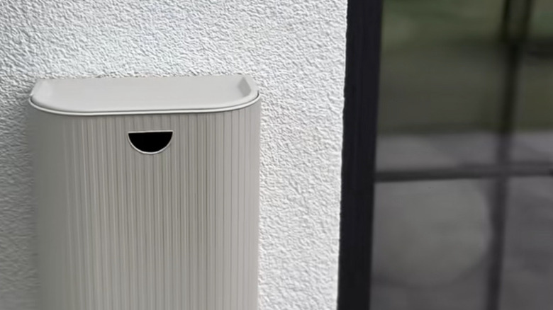 An IKEA GÅRDSBUTIK bin hanging on the wall outside the backdoor to store garden shoes.