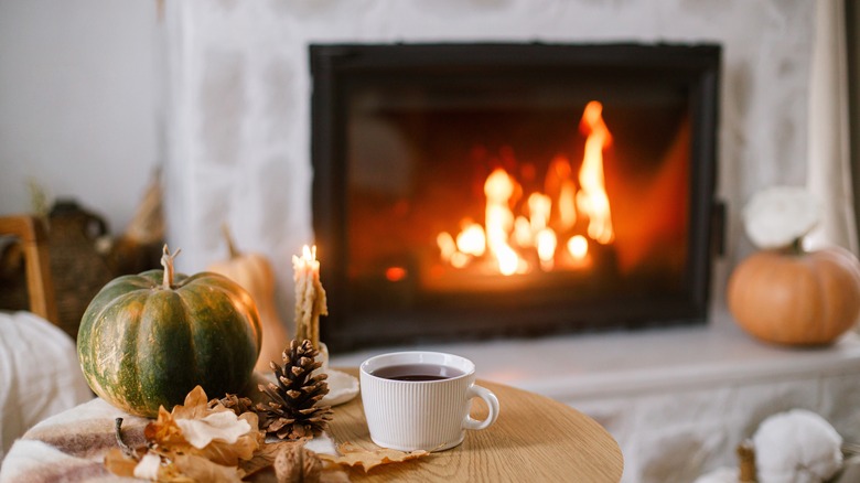 Fireplace lit in a home, a table with a cup of coffee nearby