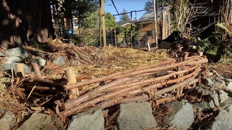 A raised garden bed made from sticks and supported by rocks.
