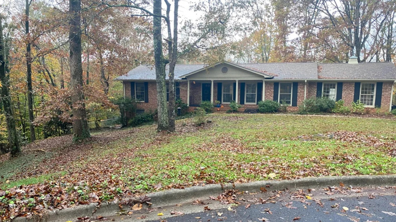 A home with a patchy lawn out the front and some trees