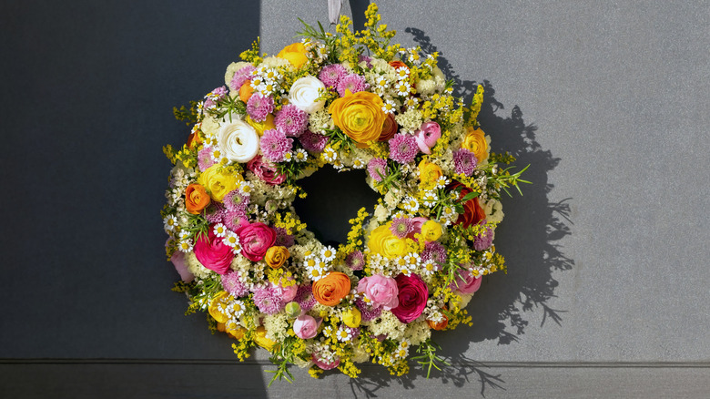A wreath styled with vibrant dried flowers for display in the spring and summer.