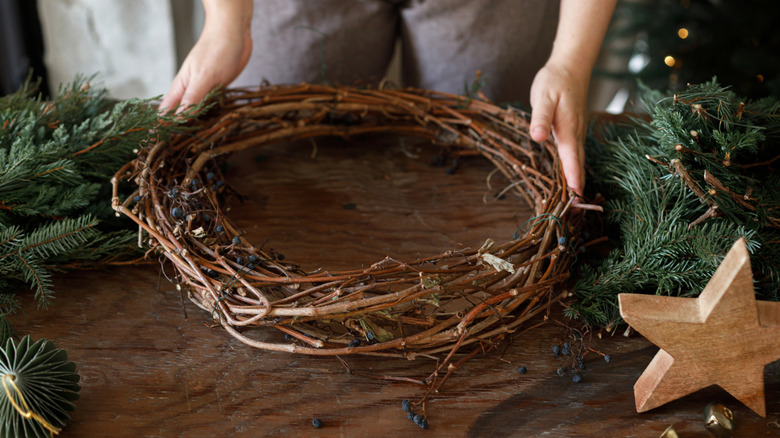 A person decorates a wreath made out of sticks.