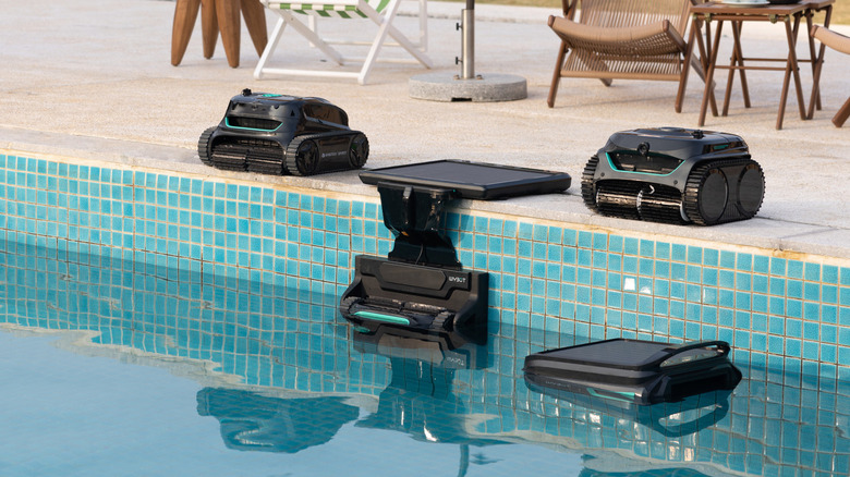 Four WYBOT robotic pool cleaners sitting along the edge of a tiled pool