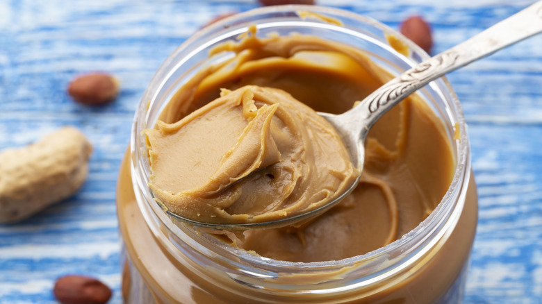 Peanut butter being scooped out of an open jar