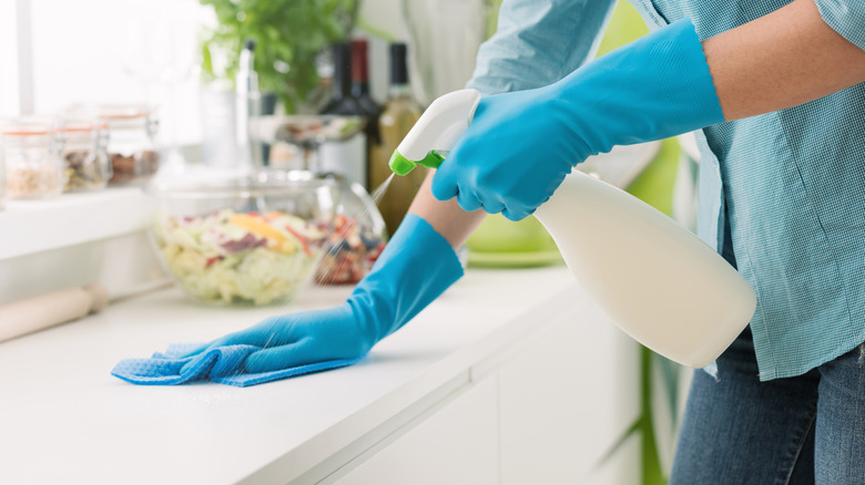 person cleaning counter with spray