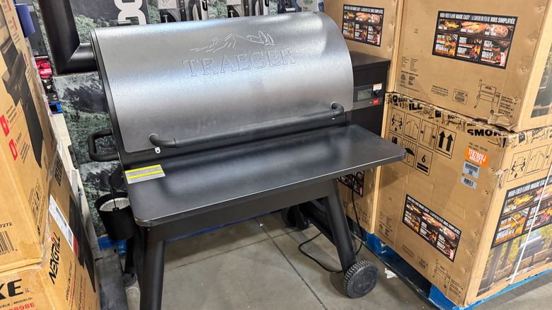An unpackaged smoker grill in between boxes of the same grill model