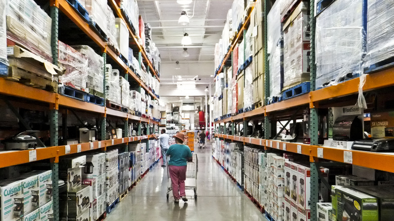 Person pushing a shopping cart down an aisle in Costco