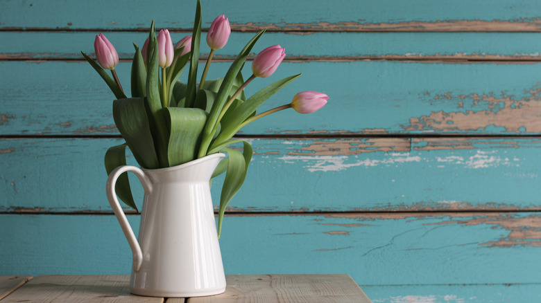 A vase of spring tulips in front of a distressed wood backdrop