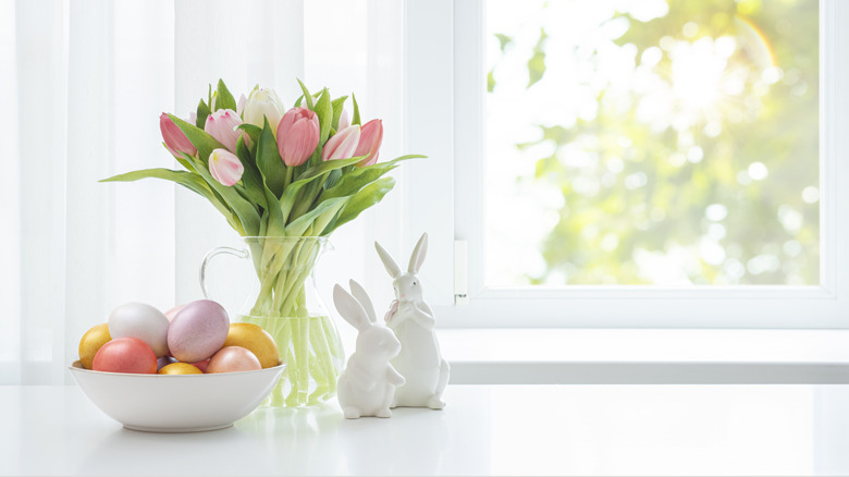 Easter eggs in a bowl next to colorful tulips