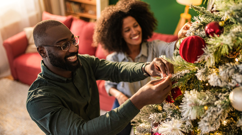 Two people decorating a Christmas tree