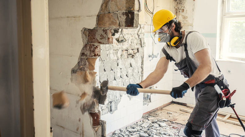A contractor knocking down a wall