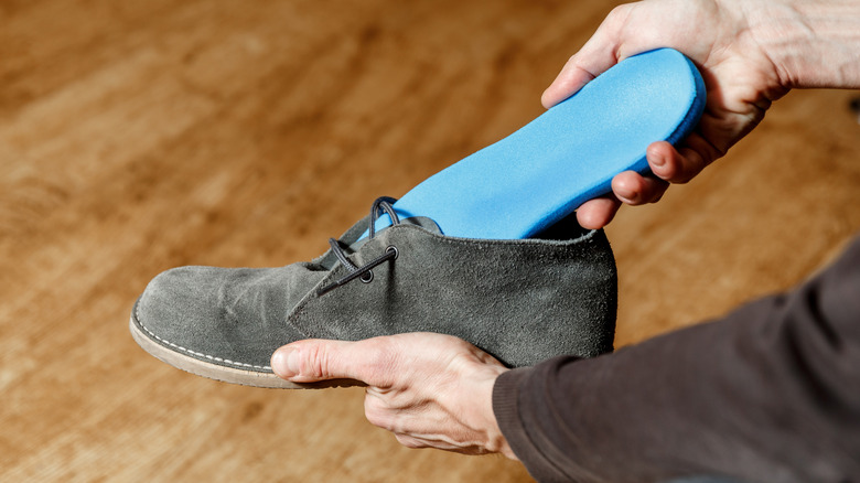 A person putting a new insole in a shoe