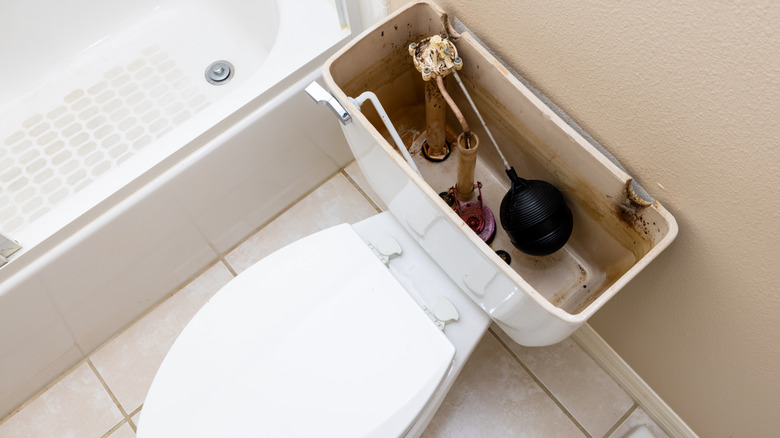 open toilet tank next to bath tub