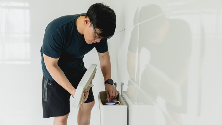 person checking toilet tank