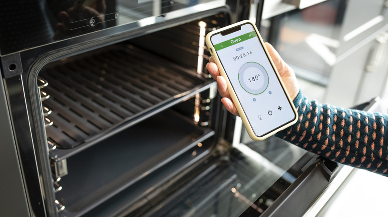 person holding phone near open oven