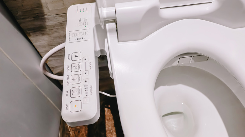 A bidet with buttons on a panel along the side of the toilet