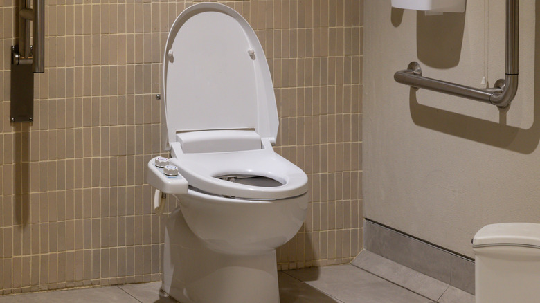 A toilet with a bidet that has two knobs for controls
