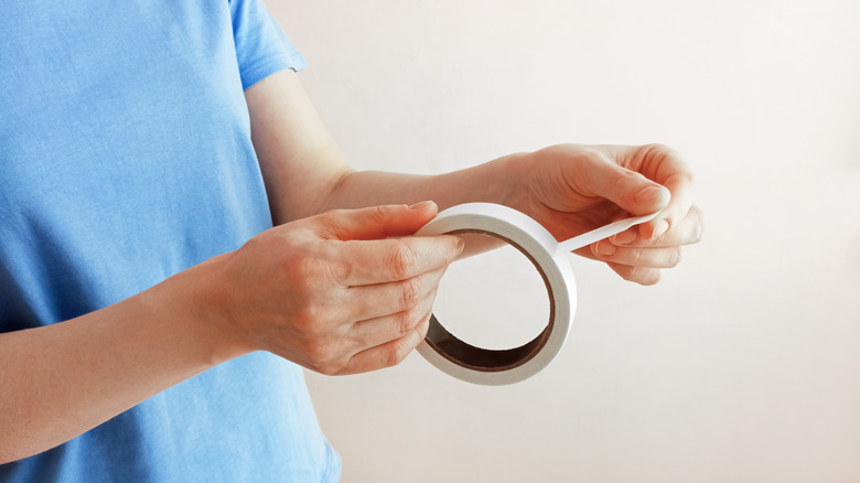 hands pulling piece of tape off roll