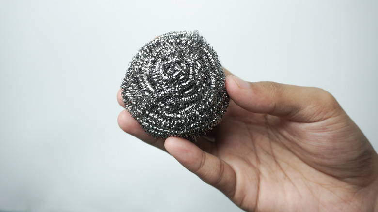 hand holding steel wool scrubber