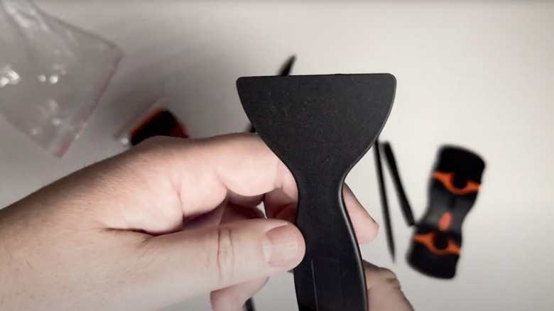 hand holding plastic scraper tool