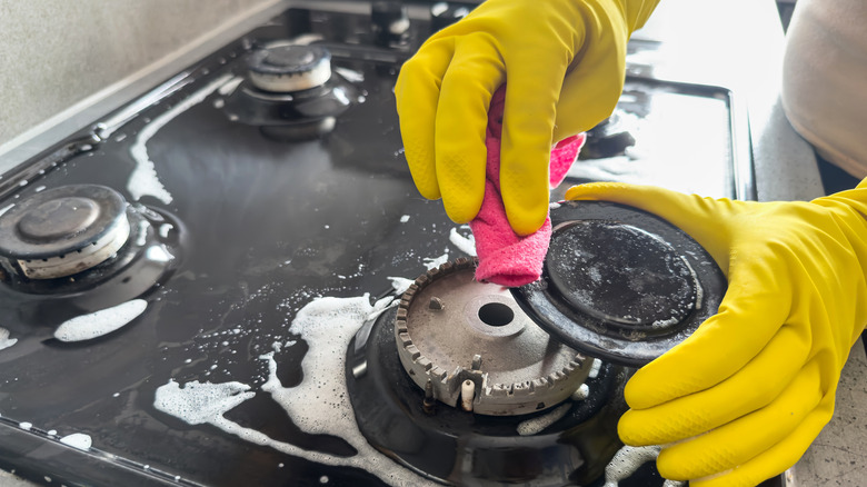 gloved hand wiping stovetop