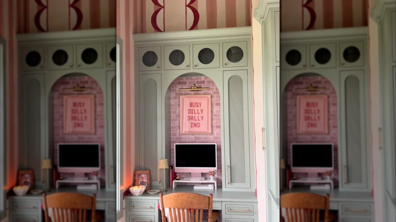 Light green desk with pink brick patterned backsplash and a stripped mural all the way to the ceiling.