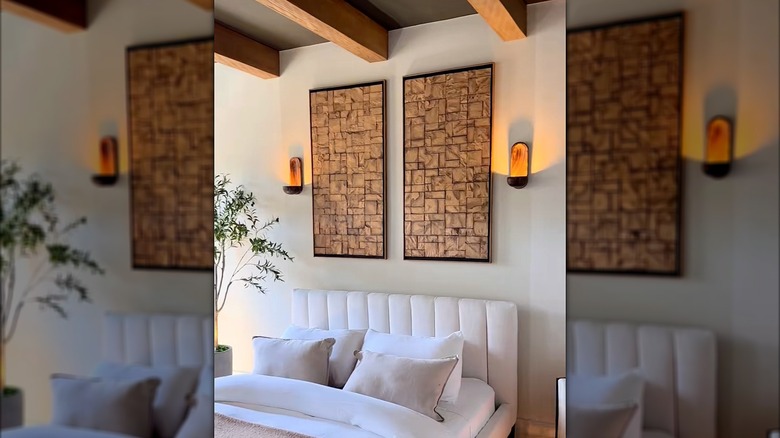 Bedroom with wood art and wood sconces with a plant in the corner and warm tones.