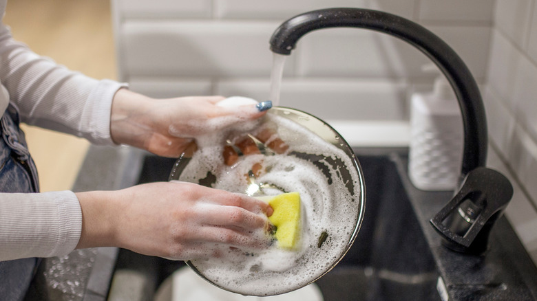Woman uses the right amount of dish soap when cleaning her dishes.