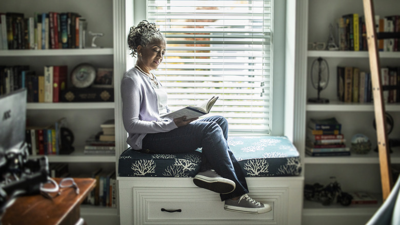 A person sitting between build-in bookcases in a reading nook