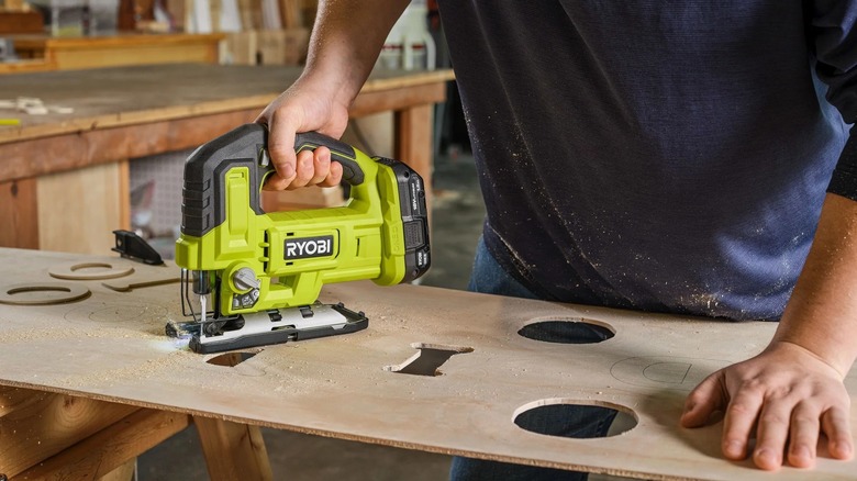 Person using a Ryobi jig saw to cut a piece of wood