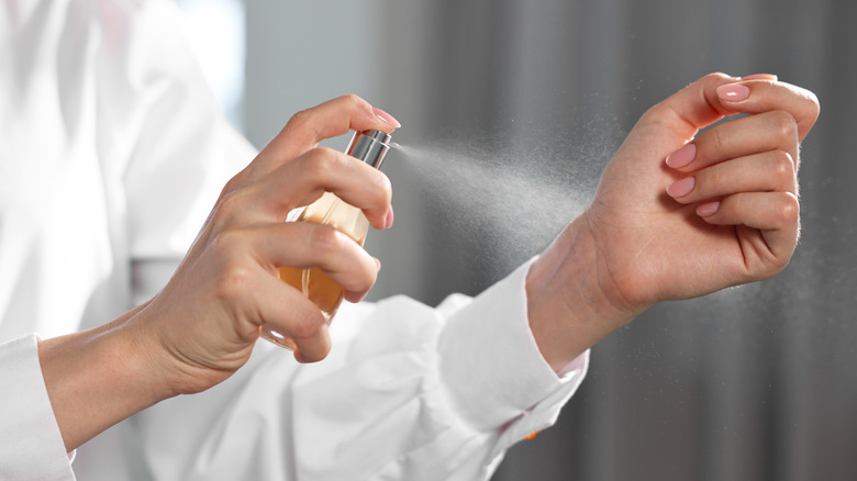 A woman sprays perfume on her wrist