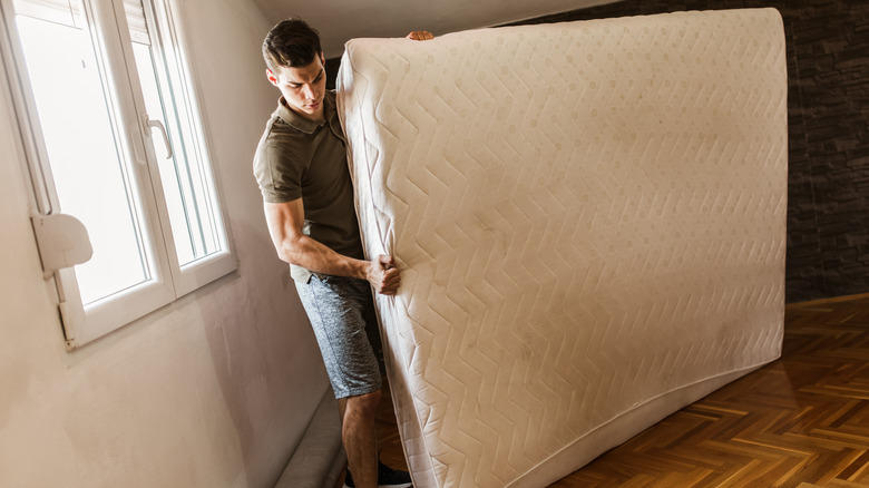 Man throwing away used mattress