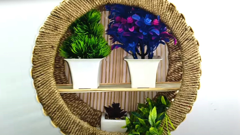 Round woven shelf with pizza box backboard and artificial plants