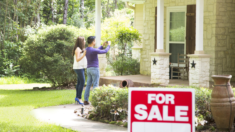 A couple checking out house with 'for sale' sign