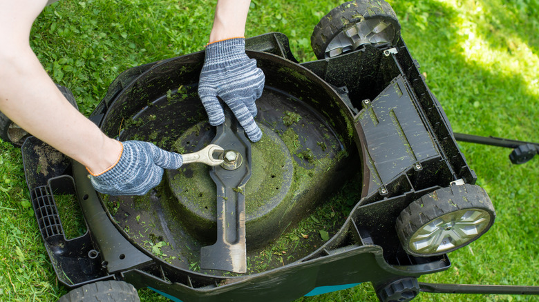 person removing lawn mower blades