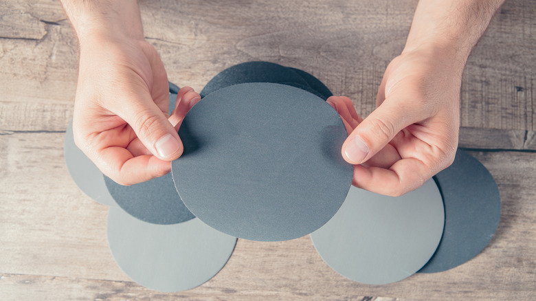 person holding sandpaper discs