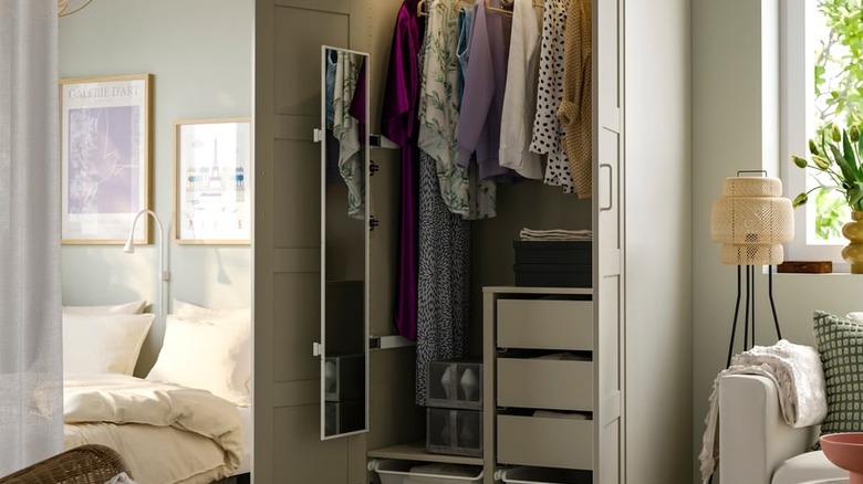 The IKEA KOMPLEMENT Pull-Out Mirror fitted to the inside of a closet full of clothes in a modern bedroom.