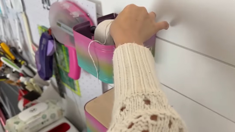 woman placing yard ball on toilet paper roll into holder in craft room