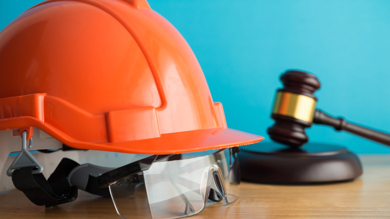A construction helmet, gavel, and safety goggles sitting on a desk.
