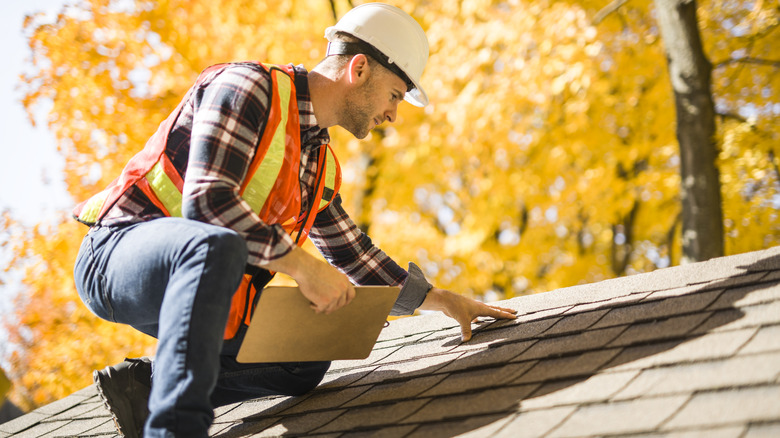 Contractor squatting down making repairs on a roof