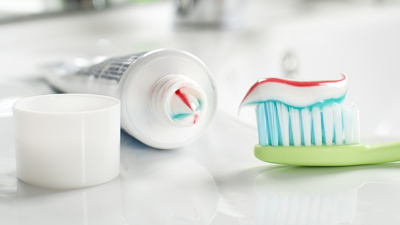 toothpaste in bottle and on toothbrush