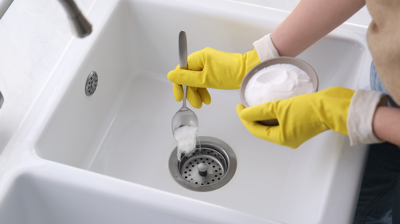 person cleaning drain with baking soda