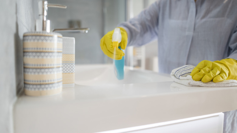 Woman spraying and cleaning a bathroom countertop