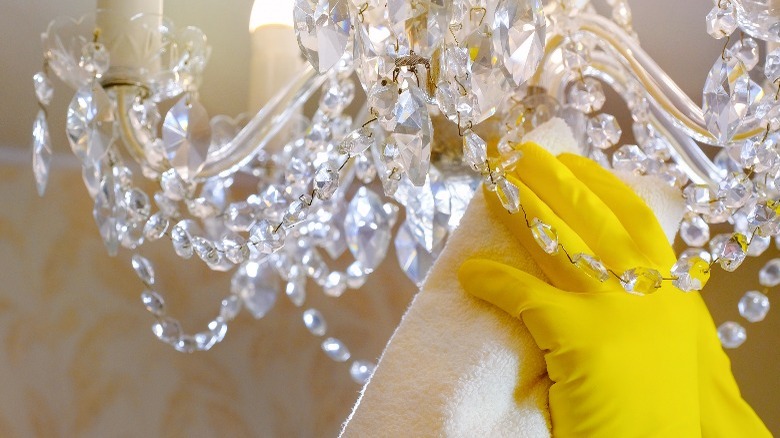 Gloved hand cleaning chandelier
