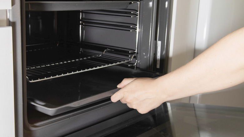 Woman removes rack from oven