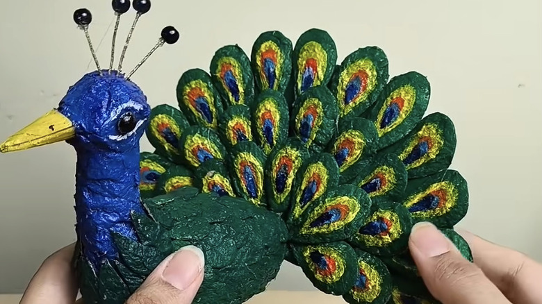 Hands holding a DIY craft peacock.