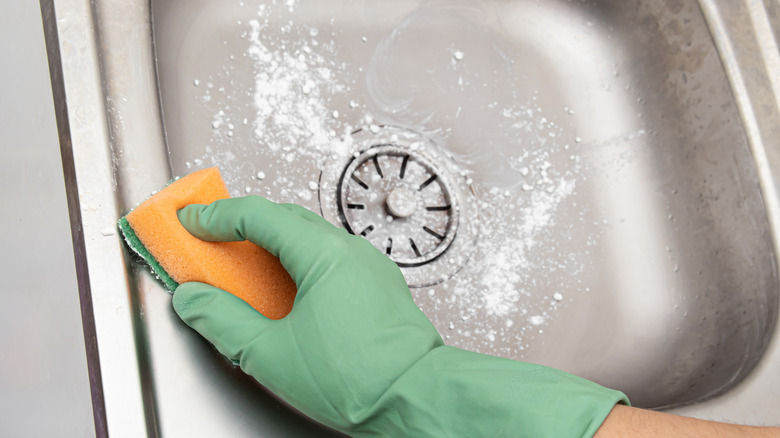 Scrubbing sink with baking soda and a sponge