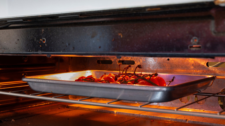 Pan of cherry tomatoes sitting under a broiler in oven